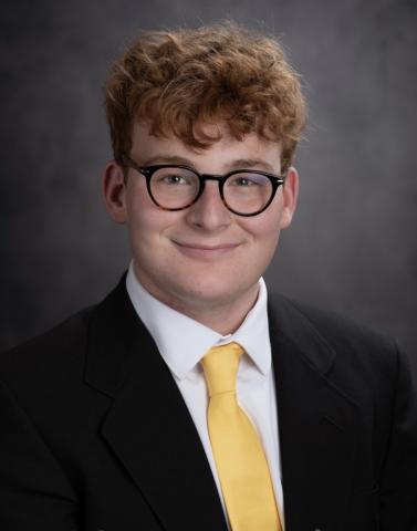 Young man in black suit, white shirt, and yellow tie